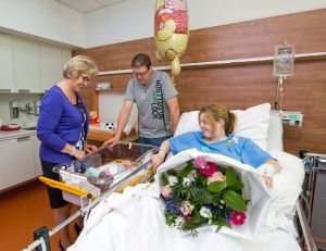 Betty van de Walle – voorzitter RvB Elkerliek ziekenhuis– overhandigt een feestelijk boeket en een welkomstpakket aan Samantha Beekers en Joris Goijaerts Zij zijn –  met baby Milan – de allereerste gasten in de nieuwe gezinssuite